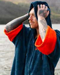 *MALE* by water wearing Dryrobe® Zip towel (blue orange)