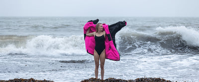 Young woman wearing black and pink Dryrobe® advance long sleeve on the beach