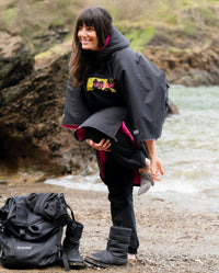 Adult female on beach wearing Dryrobe® Black pink camo remix