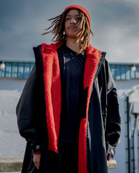 *MALE* Man stood in the sun wearing dryrobe Advance Long Sleeve changing robe in Black Red and Red dryrobe Beanie