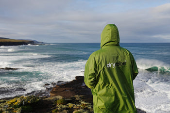 A person looking out to sea in a green dryrobe