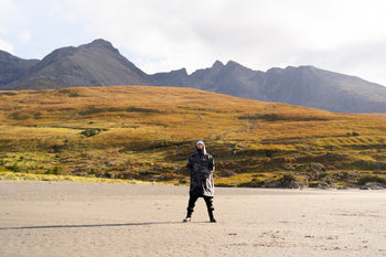 A man stood in a dryrobe with a vast landscape in the background