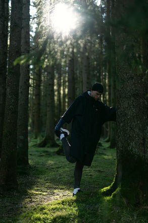 Person stretching in a forest with sunlight filtering through the trees