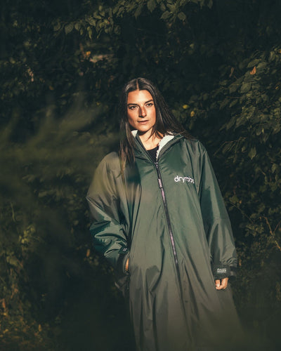 Female standing by trees wearing AW25 Green Dryrobe® advance long sleeve 