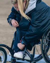 Woman sitting down, pulling up the zip on dryrobe® Adapt