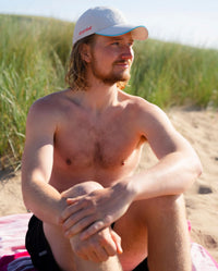 male on beach wearing grey Dryrobe® water resistant cap 