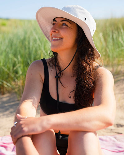 Woman on beach wearing grey Dryrobe® water resistant wide brimmed hat 