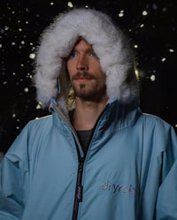 Close-up of man stood in snow, wearing dryrobe Advance Long Sleeve Alpine Range change robe in Alpine Ice Blue