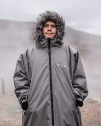 Close up of man stood on misty hill, wearing dryrobe Advance Long Sleeve Alpine Range change robe in Alpine Graphite with hood up