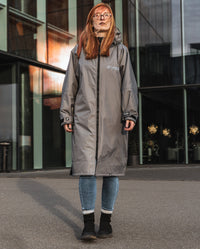 Woman stood in front of office building, wearing dryrobe Advance Long Sleeve Alpine Range change robe in Alpine Graphite 