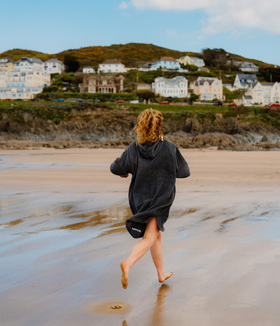 Person running on a beach with houses and hills in the background