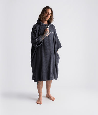 *MALE* Person wearing a dark grey poncho with a brand logo on a white background