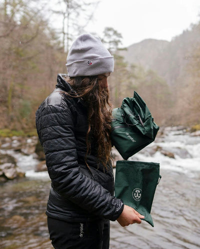 female packing Dryrobe® green poncho in front of river