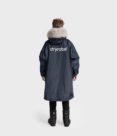 *MALE* A person shown from the back wearing a  Dryrobe with a light beige fur-trimmed hood and a white 'dryrobe' logo on the back, photographed against a light gray studio background.