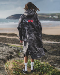 *MALE* standing facing the sea wearing Black Camo dryrobe® Advance Long Sleeve