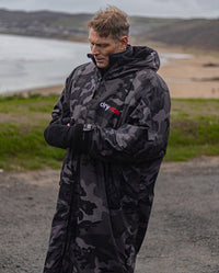 *MALE* stood in front of a beach  wearing Black Camo dryrobe® Advance Long Sleeve