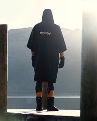 *MALE* Person stood by a lake, wearing dryrobe® Lite changing robe