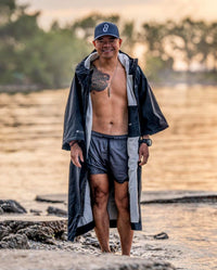 *MALE* wearing swimming gear, infront of a lake wearing dryrobe® Lite changing robe unzipped