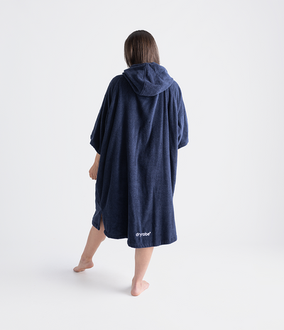 Person wearing a navy blue hooded towel robe with 'dryrobe' branding on a white background
