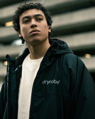 *MALE*Person wearing a black jacket with 'dryrobe' branding in an urban setting