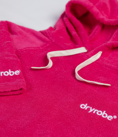 Close-up of a pink dryrobe with brand logo on a white background