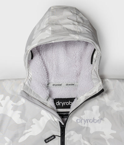 Close-up of a hooded jacket with a light gray and white camouflage pattern, featuring a soft white sherpa lining inside the hood and collar, and a black zipper with Dryrobe branding.