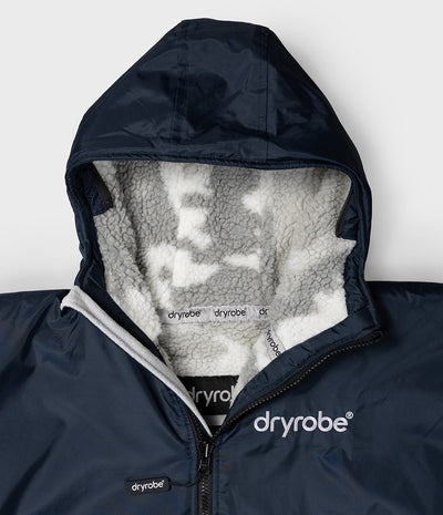 *MALE* Close-up of a navy blue hooded jacket with a white sherpa-lined hood and visible Dryrobe branding on the chest and inner lining.