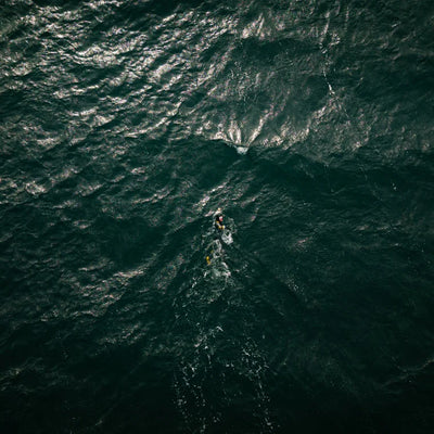 Ross Edgley swimming through dark blue ocean waves from an aerial perspective