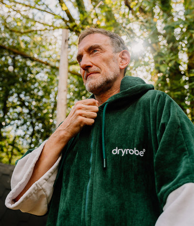 *MALE* Man wearing a green 'dryrobe' robe outdoors with trees in the background