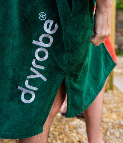 *MALE* Green towel with 'dryrobe' logo on a person's leg outdoors.