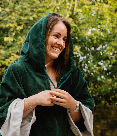Woman wearing a green hooded cloak with a blurred natural background