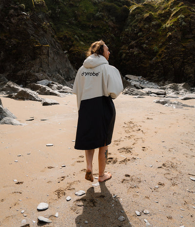 *MALE* Person wearing a Dryrobe with 'drrobe' logo on a beach