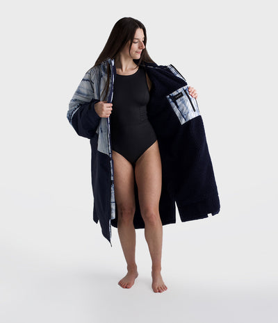 Woman wearing a black swimsuit with a matching Dryrobe on a white background
