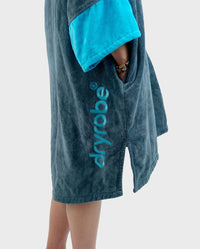 Person wearing a blue towel robe with 'dryrobe' branding on a white background