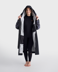 Person wearing a long dark coat with a hood on a white background