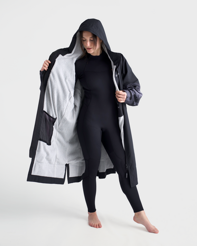 Person wearing a black and grey tech-lite changing robe with a hood on a white background