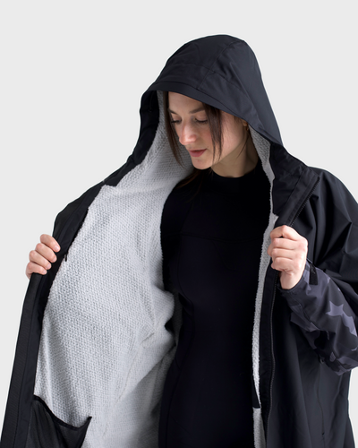 Person wearing a black and grey hooded garment against a white background