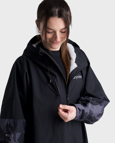 Woman wearing a black jacket with camouflage sleeves on a white background