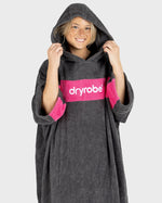 Woman smiling wearing Organic Towel dryrobe Remix in Slate Grey Pink with hood up