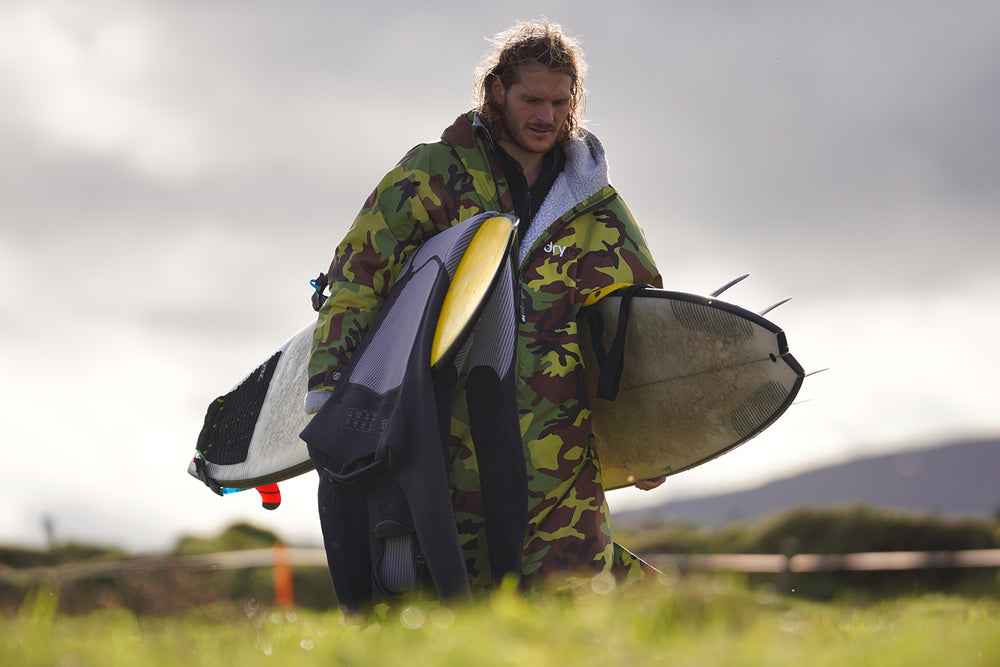 Man carrying 2 surfboards wearing a camouflage grey dryrobe Advance changing robe