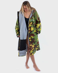 Woman stood looking at floor, wearing dryrobe Advance Long Sleeve REMIX Range change robe in Camo Grey Green