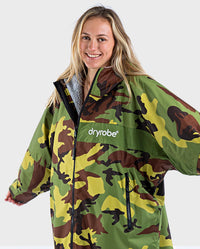 Woman smiling at camera with arms out to side, wearing dryrobe Advance Long Sleeve REMIX Range change robe in Camo Grey Green