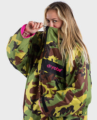 Woman wearing dryrobe Advance Long Sleeve REMIX Range change robe in Camo Pink Black, holding zip up to her nose