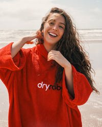 Woman smiling on a beach, wearing Red Organic Towel dryrobe®