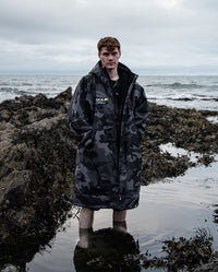 Man stood on a beach wearing OCR dryrobe® Advance Limited Edition change robe 