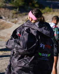 Woman walking through obstacle course wearing OCR dryrobe® Advance Limited Edition change robe 