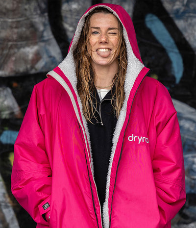 Woman with wet hair sticking tongue out, wearing dryrobe Advance long sleeve changing robe in Pink Light Grey