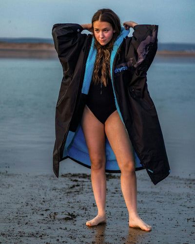 Adult female on beach wearing black blue remix Dryrobe®
