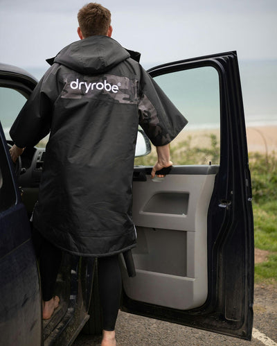 Adult male by beach wearing Dryrobe® black grey remix