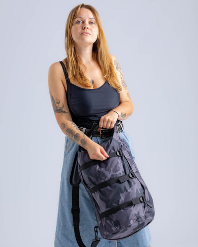 Woman in studio carrying black camo Dryrobe® compression bag 